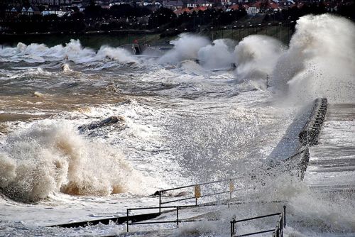 Ymchwydd storm arfordirol ym Mae Colwyn gydag amddiffynfeydd arfordirol i'w gweld.