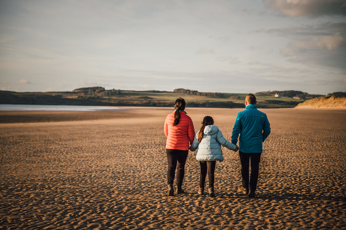 Teulu yn cerdded ar y traeth