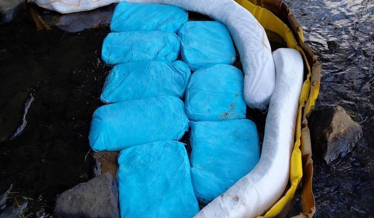 Oil pollution prevention measures deployed in a stream, including absorbent booms and absorbent pads contained within a temporary barrier, designed to capture and contain oil before it can spread downstream.