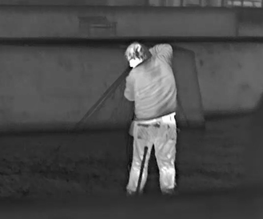 A thermal image of a man dragging a fishing net from a river