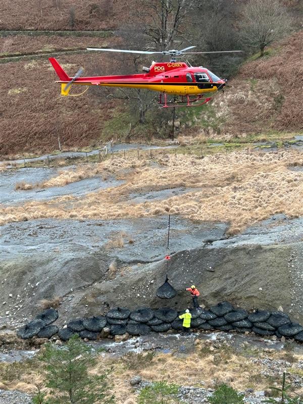 Helicopter delivering material for riverbank scour protection at Nant y Mwyn.